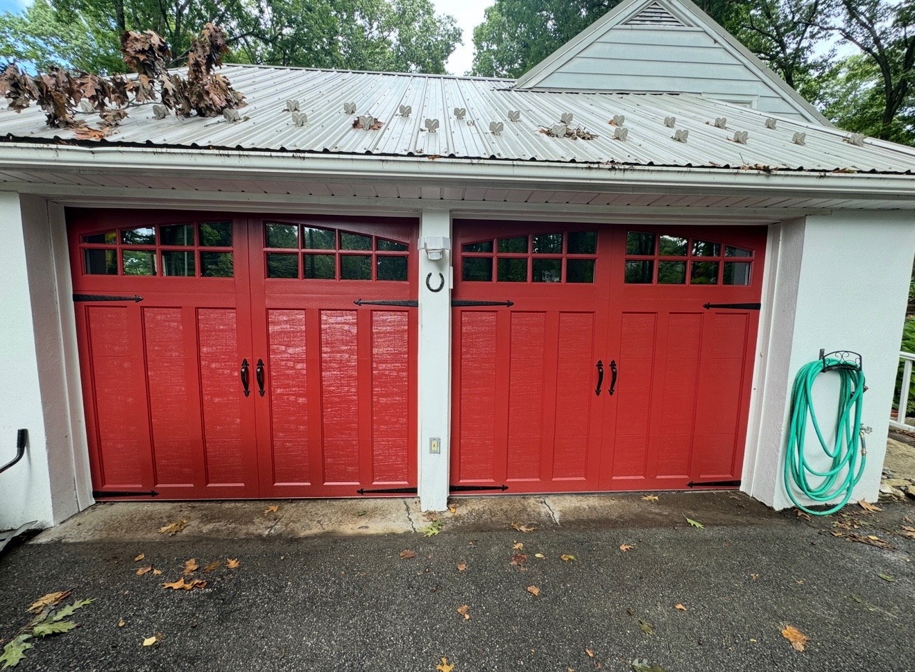 After: Beautiful red carriage-style garage doors with arched windows and decorative hardware
